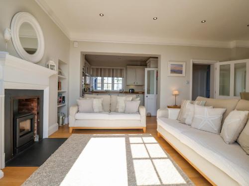 Una sala de estar con dos sofás blancos y una chimenea. en Runton, en Aldeburgh