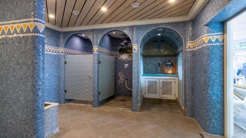 baño con paredes de azulejos azules y ducha. en Alpenhotel Oberstdorf - ein Rovell Hotel, en Oberstdorf