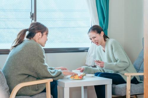 two women sitting around a table with a baby at Global Resort Misen - グローバルリゾート弥山 in Hatsukaichi