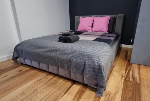 łóżko z różowymi poduszkami i szarym kocem w obiekcie Apartament Vilda 2 w Poznaniu