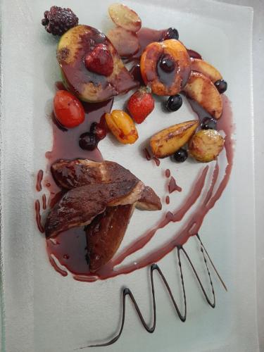 a white plate with a dessert with fruit and sauce at Logis Relais des Monedieres in Seilhac