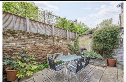 a patio with a table and chairs in front of a brick wall at Luxury Flat in the heart of South London in London