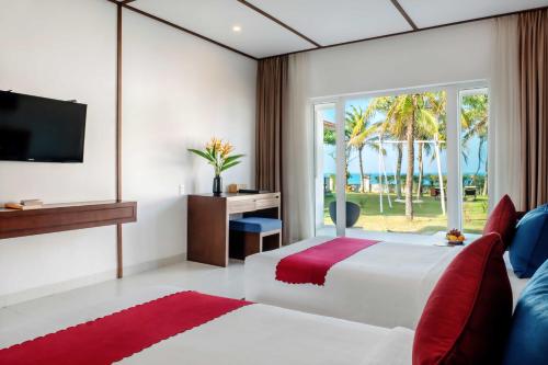 三岐的住宿－譚清海灘SPA 度假村，一间卧室设有一张床、一台电视和一个窗口。
