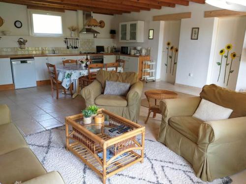 un salon avec des canapés et une table ainsi qu'une cuisine dans l'établissement La petite saunière - Chez Hélène - Gîtes en baie, à Champeaux