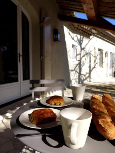 une table avec deux assiettes de pain et des tasses à café dans l'établissement La Bergerie Provencale - Luberon - Provence - villa with heated pool, à Roussillon