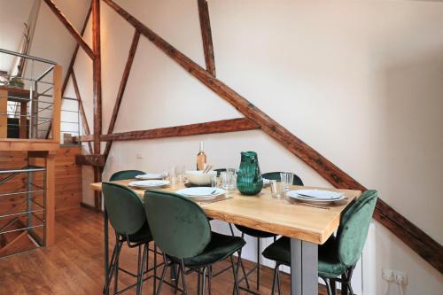 a dining room with a wooden table and green chairs at Superbe appartement esprit chalet in Barcelonnette