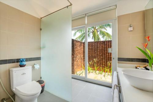 La salle de bains est pourvue de toilettes, d'un lavabo et d'une fenêtre. dans l'établissement Tam Thanh Beach Resort & Spa, à Tam Kỳ