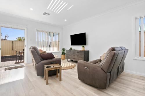 a living room with two chairs and a flat screen tv at The Shamrock House A in Renmark