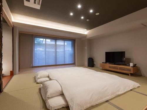 a bedroom with a large bed and a flat screen tv at Tabist kiki HOTEL KYOTO Gojo Karasuma in Kyoto
