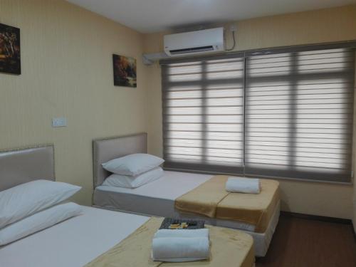 a bedroom with two beds and a window with blinds at Bintang Square Hotel in Kubang Kerian