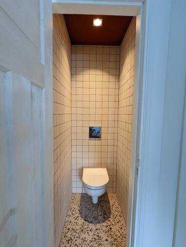a bathroom with a toilet in a tiled wall at Lost & Found 3 - with 4 bikes in Pāvilosta