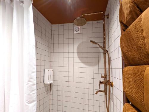 a white tiled shower with a shower curtain in a bathroom at Lost & Found 3 - with 4 bikes in Pāvilosta