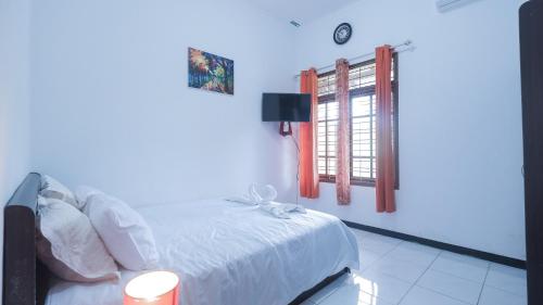 1 dormitorio con cama blanca y ventana en Villa Malang Puncak Buring en Malang