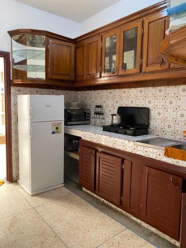 uma cozinha com um frigorífico branco e armários de madeira em Tranquil Apartment Near Agadir Anza Beach em Agadir