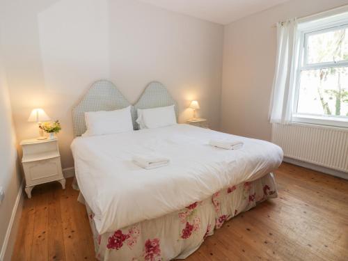 een slaapkamer met een groot bed met witte lakens en een raam bij West Lodge in Dumfries