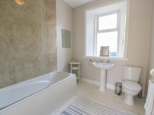 een badkamer met een bad, een toilet en een wastafel bij West Lodge in Dumfries