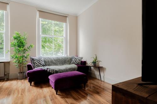 a living room with a couch and a chair and windows at flat C 1-Bed Flat in Primrose Hill wont be avilbe in London