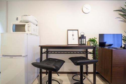 a kitchen with a table and two stools next to a refrigerator at Chez Moi royale in Tokyo