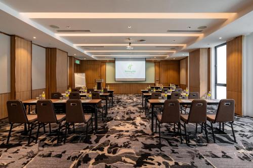 a conference room with tables and chairs and a projection screen at Holiday Inn Sepang - Airport in Sepang