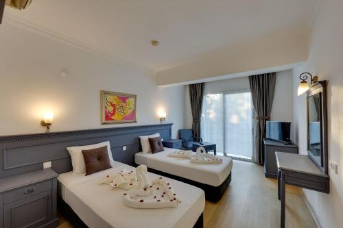 Cette chambre comprend deux lits et une télévision. dans l'établissement Sapphire Club Hotel, à Bodrum City