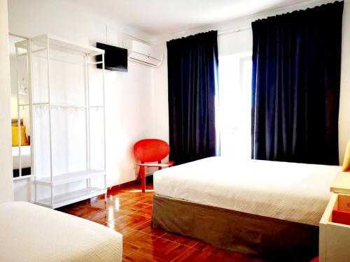 1 Schlafzimmer mit 2 Betten und einem roten Stuhl in der Unterkunft Bulldog Inn - Duna Parque Resorts & Hotels in Vila Nova de Milfontes