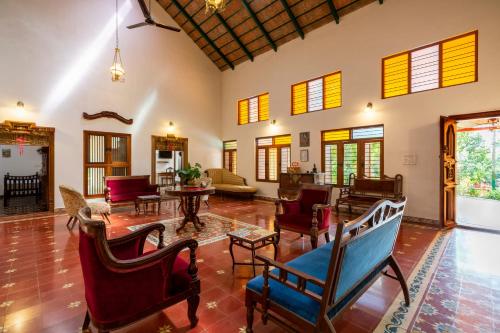 an open living room with chairs and tables at amã Stays & Trails, Rare Earth Estate in Madikeri