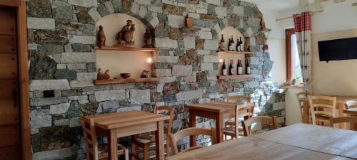 un ristorante con tavoli in legno e un muro di pietra di Le Coin des Mélèzes - NATURE & TREK a Brusson