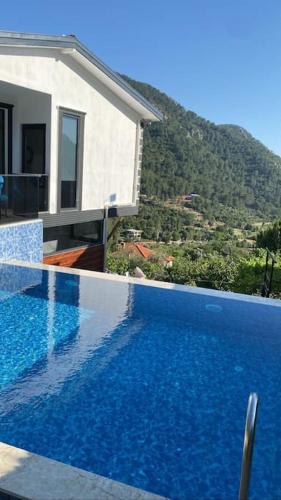 a large blue swimming pool next to a house at Villa Camgüzeli Kivili Konak’ta! in Fethiye
