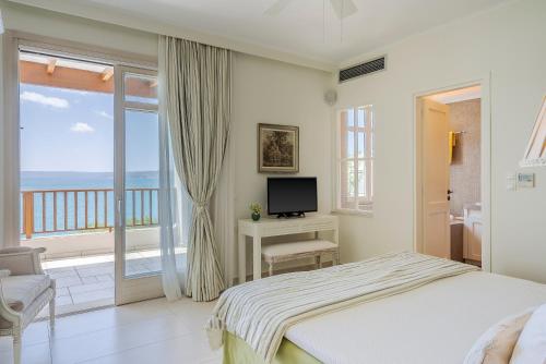 a bedroom with a bed and a television and a balcony at SK Place Luxury Seafront Villas Chania in Almyrida