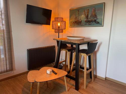 a room with a table and a desk with a lamp at Joli studio près du front de mer in Cabourg