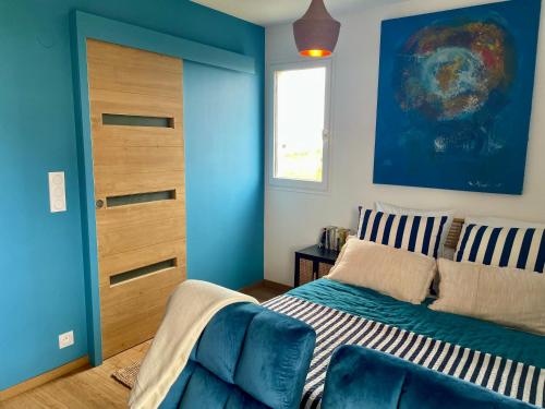 une chambre avec un lit et un mur bleu dans l'établissement Joli studio près du front de mer, à Cabourg
