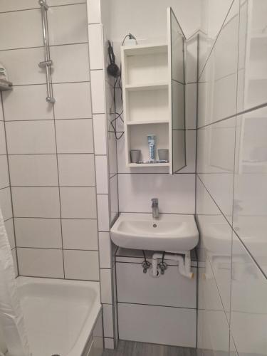 ein weißes Bad mit einem Waschbecken und einer Dusche in der Unterkunft Apartment 16 - 2R1 in Essen