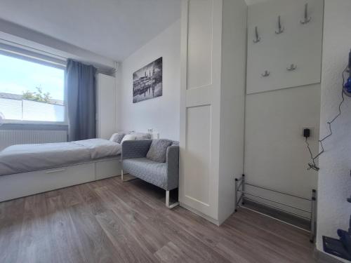 ein Schlafzimmer mit einem Bett, einem Stuhl und einem Fenster in der Unterkunft Apartment 16 - 2R1 in Essen