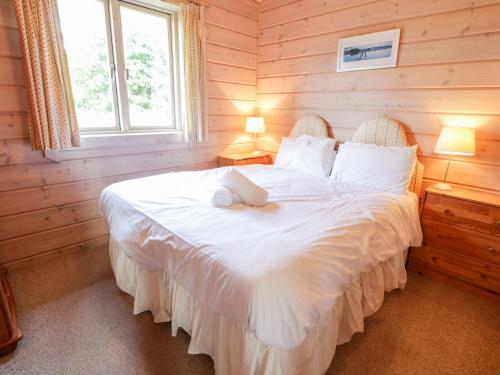 a bedroom with a large white bed with two lamps at Curlew Lodge in Dumfries