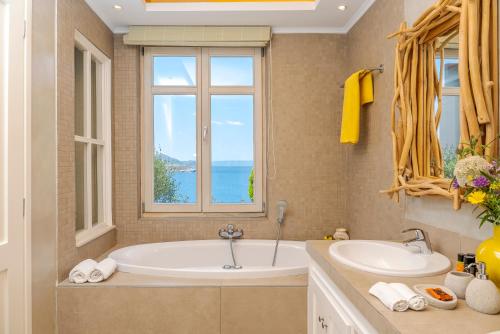 a bathroom with a tub and a sink and a window at SK Place Luxury Seafront Villas Chania in Almyrida