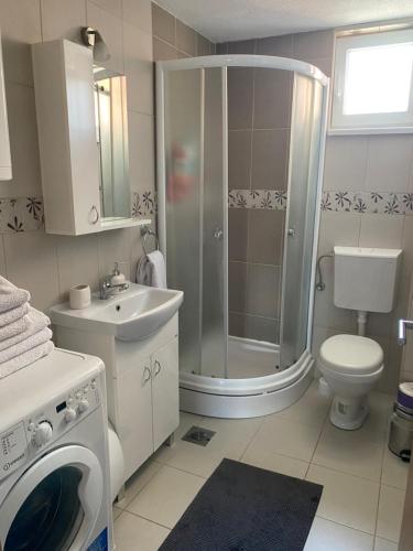 a bathroom with a shower sink and a washing machine at MKA suite in Kragujevac