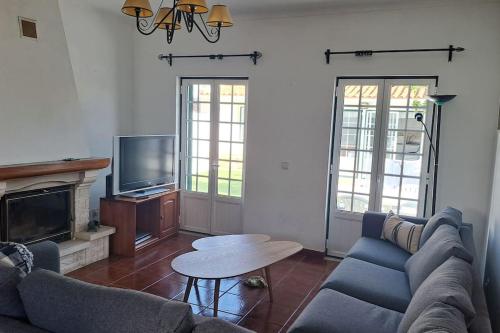 a living room with a couch and a table and a tv at Casa Melides perto Comporta in Melides