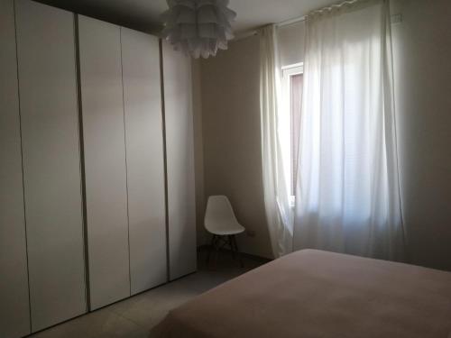 a bedroom with a bed and a window and a chair at Maresol apartment in Carrara