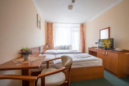 Habitación de hotel con 2 camas, mesa y escritorio en Hotel SOREA SNP en Demanovska Dolina