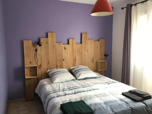une chambre avec un grand lit avec une tête de lit en bois dans l'établissement Maison de vacances au calme, à Angles