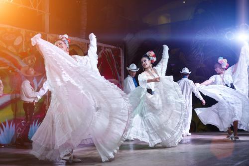 a group of women in white dresses dancing on a stage at Occidental Costa Cancún - All Inclusive in Cancún