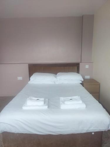 a large white bed with two towels on it at Tadross Hotel in Barry