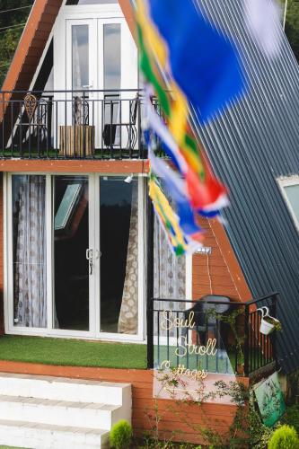 a house with a balcony and a flag in front of it at The Soul Stroll Cottages Retreat in Mukteswar
