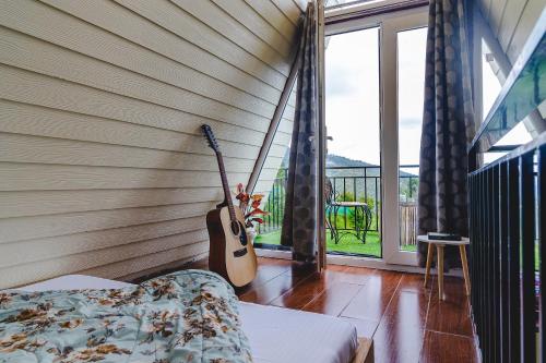 a room with two guitars on the wall next to a window at The Soul Stroll Cottages Retreat in Mukteswar