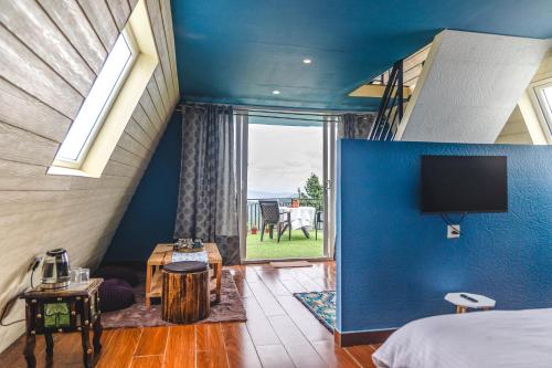 1 dormitorio con una pared azul y TV. en The Soul Stroll Cottages Retreat en Mukteswar