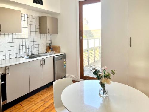 a kitchen with a table with a vase of flowers on it at Victorian Terrace in the heart of it all! in Melbourne