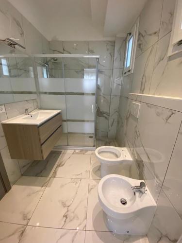 a white bathroom with a toilet and a sink at Pinetina Beach in Bibione