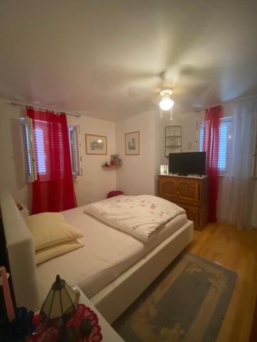 a bedroom with a bed and a tv and red curtains at Cozy Room + shared kitchen + shared bathroom + free parking in Hvar