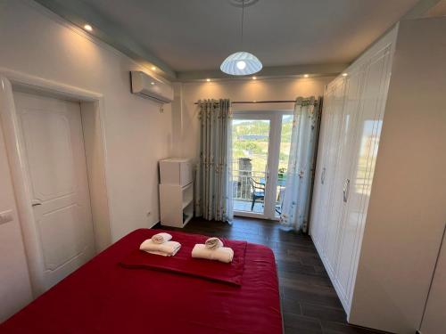 sypialnia z 2 ręcznikami na czerwonym łóżku w obiekcie Adriatik Guesthouse w mieście Përmet
