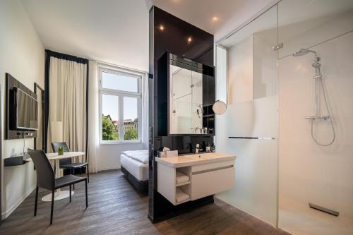 ein Bad mit einem Bett, einem Waschbecken und einem Spiegel in der Unterkunft INNSiDE by Meliá Leipzig in Leipzig